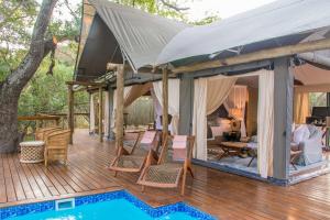 a large deck with chairs and a tv on it at Rhino Sands Safari Camp in Manyoni Private Game Reserve