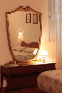 a mirror on a dresser with a bed in a bedroom at B&B Corte Barbieri in Dolcè