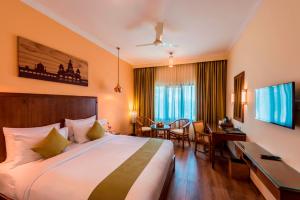 a hotel room with a large bed and a desk at Regenta Central Herald Mysore in Mysore