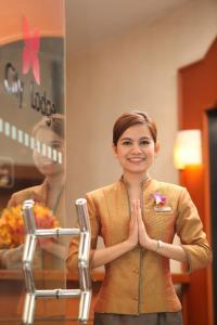 a woman standing in front of a mirror praying at City Lodge Bangkok in Bangkok