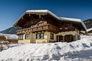 een huis met sneeuw op de grond ervoor bij Ferienhaus Hubertus - PRECHTLHOF in Flachau