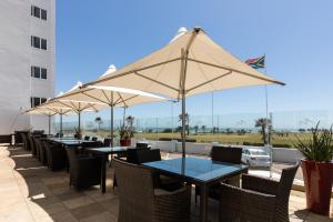 a patio area with tables, chairs and umbrellas at Southern Sun The Marine in Port Elizabeth