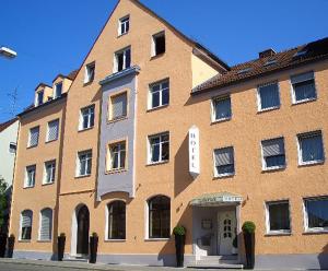 een groot oranje bakstenen gebouw met een witte deur bij Hotel Augsburg Goldener Falke in Augsburg