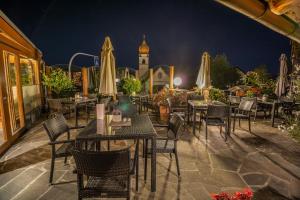 ソプラボルツァーノにあるDrei Birkenの夜のテーブルと椅子、パラソル付きのレストラン