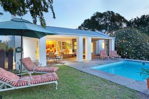 a house with a pool and chairs and an umbrella at Marshden Estate in Stellenbosch