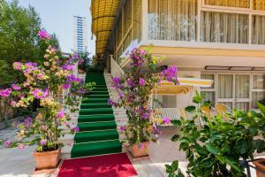 ein Gebäude mit einer grünen Treppe mit lila Blumen in der Unterkunft Hotel Donatello in Cesenatico