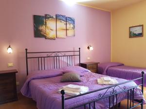 a bedroom with two beds with purple sheets at Hotel Il Cortile in Custonaci