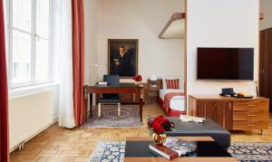 uma sala de estar com uma cama e uma secretária com uma televisão em Living Hotel an der Oper em Viena
