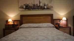 Hotel Puente Romano في ألكانتارا: غرفة نوم مع سرير مع مواقف ليلتين ومصباحين