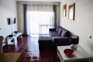 a living room with a couch and a large window at Alveiros Apartamentos Praia dos Aveiros in Albufeira