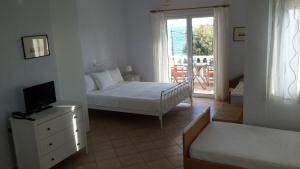 1 dormitorio con 2 camas, TV y ventana en Akti Zaga Apartments, en Koroni