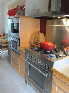 a kitchen with a stove with a red pot on it at les maisons blanches in Weris