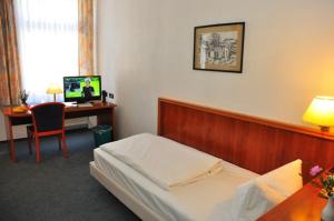 a bedroom with a bed and a desk with a computer at Brocki's Hotel Stadt Hamburg in Parchim