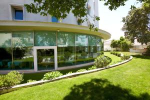 un grand bâtiment avec des fenêtres en verre sur une pelouse dans l'établissement Hotel Santa Maria, à Fátima