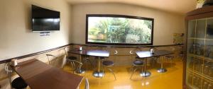 a meeting room with tables and stools in front of a window at Hotel Casarola - Trigoria in Castel di Decima