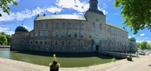 un gran edificio de piedra con un estanque delante de él en 27ans Nattlogi, en Vadstena