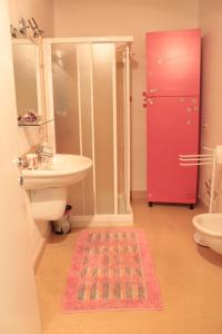 baño con lavabo y aseo y puerta roja en B&B Corte Barbieri, en Dolcè