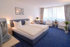 a hotel room with a bed and a television at HAK Hotel am Klostersee in Sindelfingen