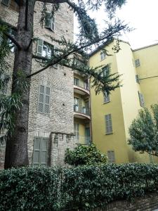 un grand bâtiment avec un arbre en face dans l'établissement Le Logge, à Parme