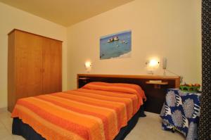 a bedroom with a bed with a orange striped bedspread at Residence Oasi Salento in Torre dell'Orso +38 photos