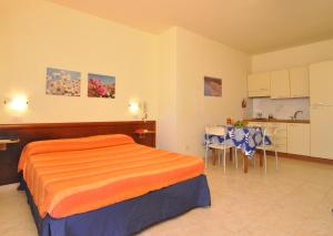 1 dormitorio con cama, mesa y cocina en Residence Oasi Salento, en Torre dell'Orso