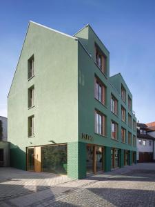 ein Gebäude mit einer grünen und weißen Fassade in der Unterkunft Kitz Boutique Hotel & Restaurant in Metzingen