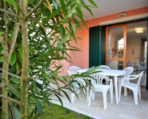 a group of white chairs and a table on a patio at Magica immobiliare - Milano Dune 33 in Lido di Jesolo