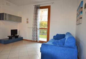ein Wohnzimmer mit einem blauen Sofa und einem TV in der Unterkunft Magica immobiliare - Milano Dune 33 in Lido di Jesolo