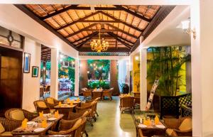 un restaurante con mesas y sillas y una lámpara de araña en Royal Orchid Metropole Mysore en Mysore