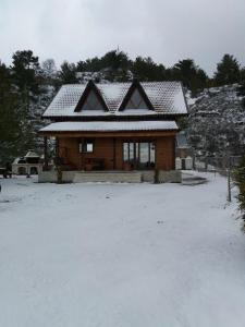 une maison avec un toit recouvert de neige dans l'établissement Agros Timber Log House, à Agros