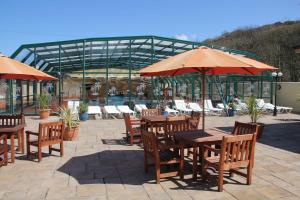 卡迪根的住宿－Cardigan Bay Holiday Park，一个带桌子和遮阳伞的庭院和一个游泳池