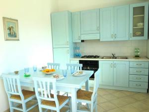 a white kitchen with a white table and chairs at Agriturismo Pentuma in Chiaramonti