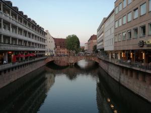 eine Brücke über einen Fluss in einer Stadt mit Gebäuden in der Unterkunft Ferien - und Messewohnung am Wöhrder See in Nürnberg