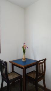 una mesa con dos sillas y un jarrón con flores. en Atobá Villas, en Paraty