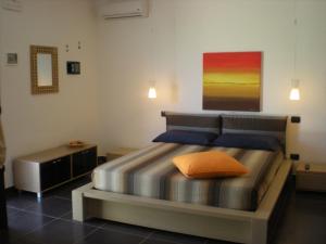 B&B Terra Marique في سيراكوزا: غرفة نوم مع سرير مع وسادة برتقال عليه