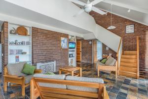 a living room with a couch and a brick wall at Bay Retreat Port Arthur in Port Arthur