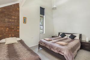 a bedroom with two beds and a brick wall at Bay Retreat Port Arthur in Port Arthur