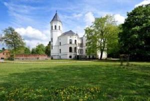 ein großes weißes Gebäude mit einem Turm auf einem Feld in der Unterkunft Schlosshotel Bredenfelde in Bredenfelde