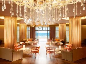 a lobby with chairs and tables and a chandelier at Grecotel Astir Alexandroupolis in Alexandroupoli