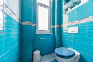 uma casa de banho azul com um WC e uma janela em A43 Apartment em Budapeste