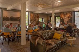 a group of people sitting at tables in a room with a couch at Bed & breakfast Hoeve Springendal in Hezingen