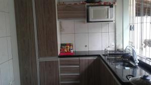 a kitchen with a sink and a microwave at Casa em Arraial d'Ajuda in Arraial d'Ajuda