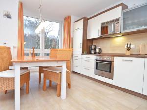eine Küche mit einem Tisch und Stühlen sowie eine Küche mit weißen Schränken in der Unterkunft Haus Möwe - Apt. 07 in Ostseebad Sellin