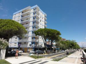 um edifício de apartamentos alto e branco numa rua da cidade em Bel Sole - Appartamenti em Bibione