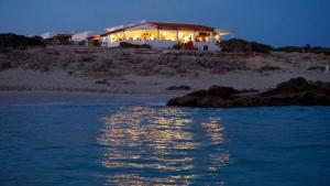 a house on the beach at night with lights at Apartamentos La Fragata in Es Arenals