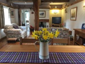 um vaso com flores amarelas numa mesa numa sala de estar em Charming Welsh Cottage em Johnston