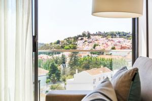 a living room with a couch and a large window at Octant Santiago in Santiago do Cacém