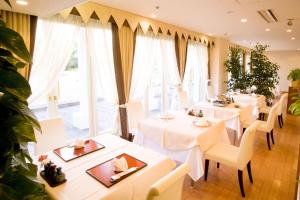 ein Restaurant mit weißen Tischen, Stühlen und Fenstern in der Unterkunft Tokyo Grand Hotel in Tokio