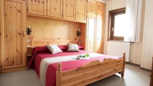 sypialnia z dużym drewnianym łóżkiem z różową pościelą w obiekcie Tea Bastian w Livigno