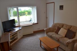 a living room with a couch and a tv at CopperTree Cottage in Torquay